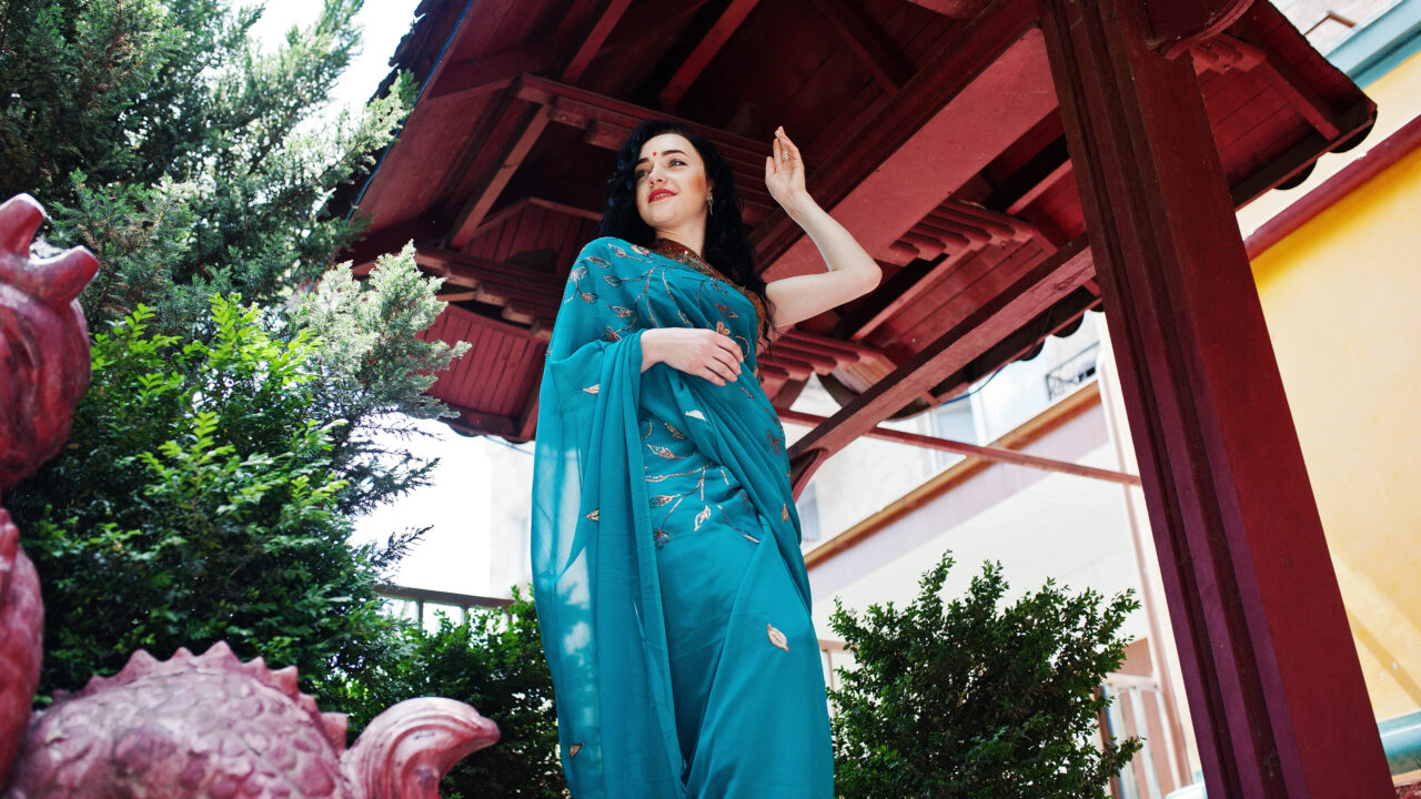 Portrait of beautiful indian brumette girl or hindu woman model against japanese traditional house and dragon figure.